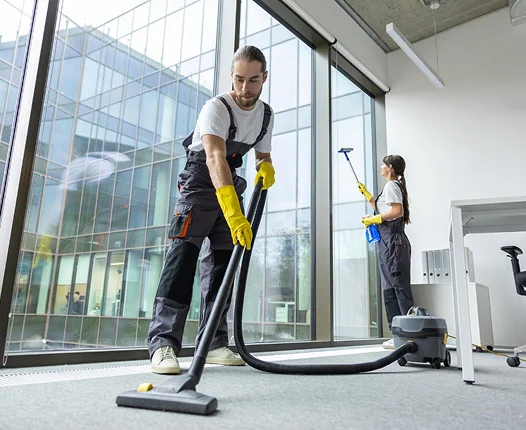 Professionele schoonmakers werken in een helder kantoor, stofzuigen vloeren en reinigen glazen oppervlakken om een schone en productieve werkplek te behouden.